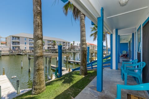 Relax on your private waterfront patio with turquoise chairs, swaying palms, and direct access to the marina—your tropical escape awaits.