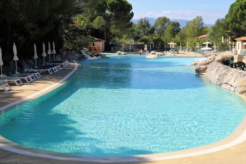 Guests cooling off in the pool, with the wooded Ardèche hillside rising behind the residence.