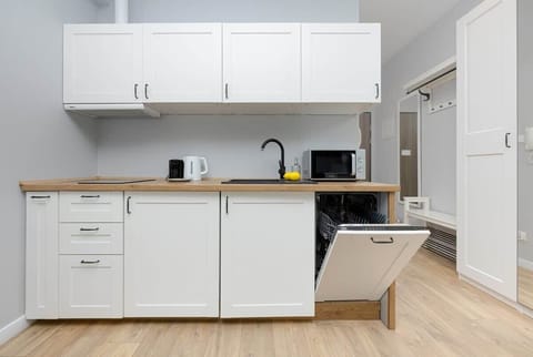 A functional, open-plan kitchen with sleek white cabinets, a black sink, and wooden countertops.