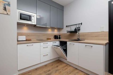 A modern kitchen with white cabinetry, wooden countertops, and integrated appliances.