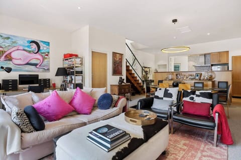 Bask in the vibrant atmosphere of the spacious living room, featuring retro furnishings, a comfortable sofa, leather armchairs, and a TV—perfect for relaxing after a day exploring Hobart.

