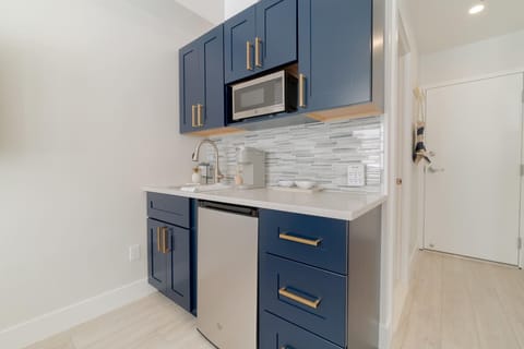 Kitchenette with a microwave, mini fridge, Keurig coffee maker, glasses, plates, and cutlery. 