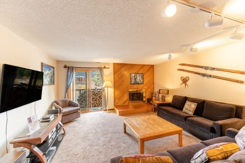 Relax in your cozy living room with vintage ski decor, crackling fireplace, and mountain views through the patio doors.