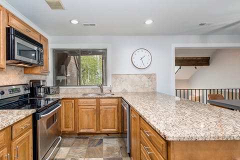 Kitchen with stone countertops, stainless steel appliances, bar seating for four, and garage and laundry room access