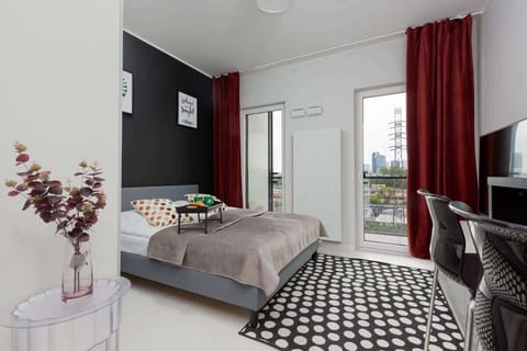 A modern bedroom with a double bed standing on one of the walls, which is in black. Maroon curtains hang in the windows, which add elegance to the room.