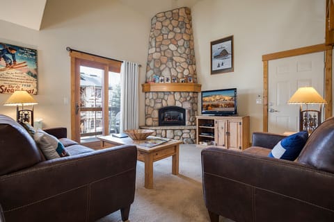 Sink into plush leather seating by your cozy stone fireplace, where warm light and mountain charm create the perfect retreat.