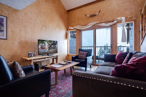 Unwind in your southwestern-inspired living room with plush seating, flat-screen TV, and stunning mountain views from your private balcony—your cozy retreat awaits.
