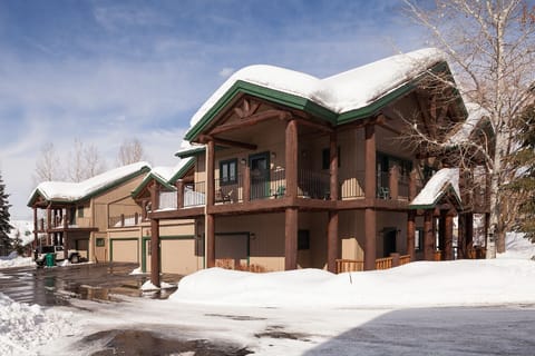 Mountain lodge with snow-covered roofs and wooden architecture nestled in winter landscape.