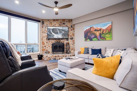 Sink into plush seating by your cozy stone fireplace, where mountain views and vibrant artwork create the perfect alpine retreat.