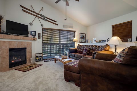 Cozy up in your mountain retreat living room with a crackling fireplace, comfortable leather seating, and charming ski décor overhead.