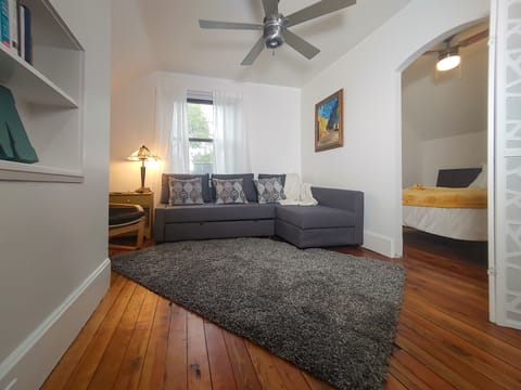 The living room includes a SMART TV, books, and a convertible couch bed.