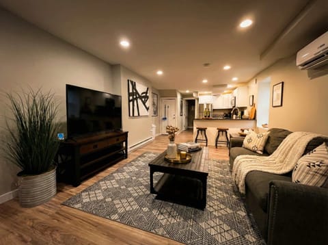 Open living area with sofa seating, TV, coffee table, and kitchen nearby.