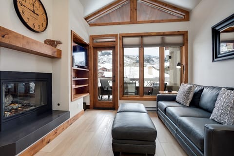 Cozy up by your fireplace while soaking in stunning mountain views through floor-to-ceiling windows in this alpine living room.