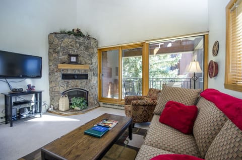 Unwind by your stone fireplace while enjoying tree views from the private balcony in this cozy living space.