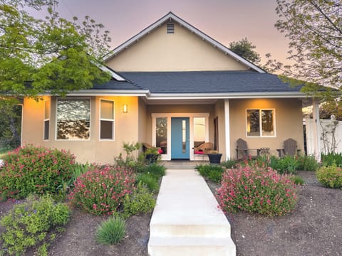 The home’s covered entry is framed by garden beds and a straight walkway.