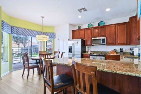 Modern kitchen with granite countertops, stainless appliances, and a bright dining area.