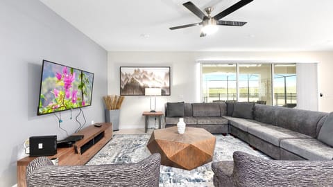 Modern living room with a gray sectional, geometric table, and wall art.