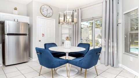 Sleek kitchen nook with plush blue chairs and a chic marble clock.