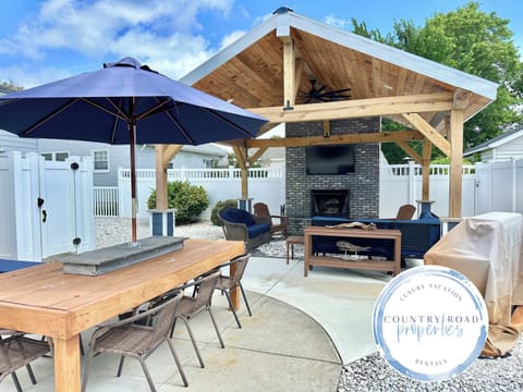 Savor alfresco meals at the spacious wooden dining table in your private backyard. This inviting space connects to a luxury covered lounge with a stone fireplace and TV, creating the ultimate setting for vacation entertaining.