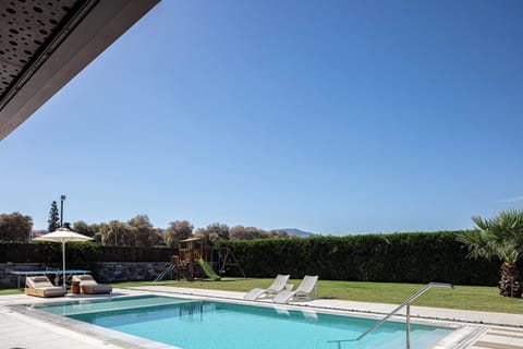 Large lawned garden by the pool area, featuring a children’s play structure with swings and slides and table tennis.