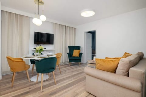 Bright and cozy living room with a mustard-yellow sofa, green accents, and plenty of natural light — perfect for relaxation after a beach day.