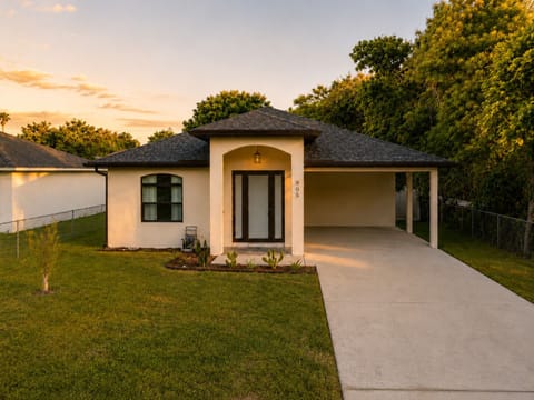 A single-story home under a sunset sky with the carport and lawn ready for you
