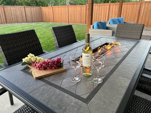 Enjoy a beautiful time outside with a fenced backyard, covered patio, green grass, and the table fire pit. 