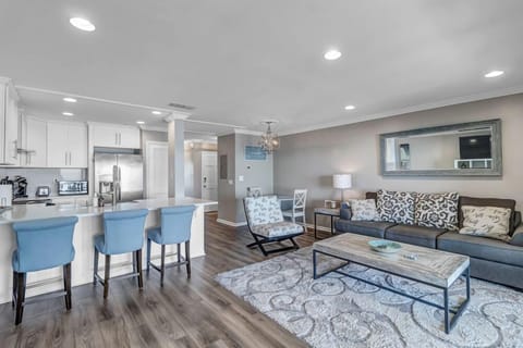 - Stylish open layout features a plush sectional, patterned chair, and calming tones
- Fully equipped kitchen with island seating and pendant lighting for easy dining
- Wood look floors and coastal accents create a breezy, modern retreat