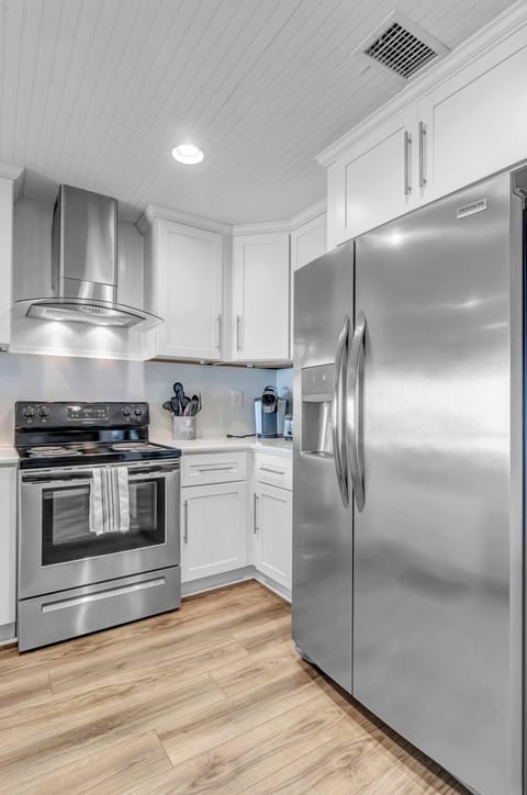 - Enjoy a fully stocked kitchen with stainless steel appliances, including a large fridge
- Sleek white cabinetry and modern hardware elevate the space with clean style
- Coffee maker, utensils, and essentials are ready for your stay
