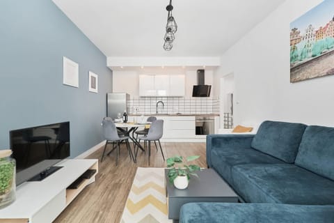 Living room with a sofa, TV and kitchenette.