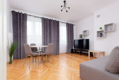 A bright, airy living room featuring a gray sofa, contemporary decor, and wooden flooring. Natural light enhances the inviting ambiance.