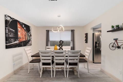 Gather around the dining table beneath modern pendant lighting, with a fully stocked kitchen just steps away for easy meals and connection.