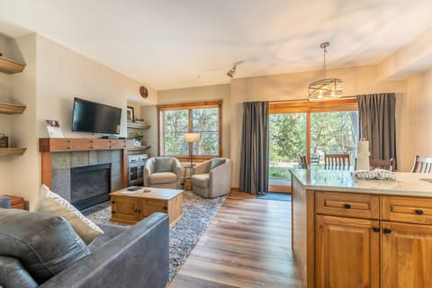 Relax in your cozy living space with warm fireplace, comfy seating, and natural light streaming through large windows.