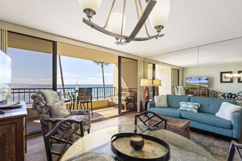 Sink into the teal sofa and soak in stunning ocean views through floor-to-ceiling glass doors that open to your private balcony, where gentle breezes and palm trees await.