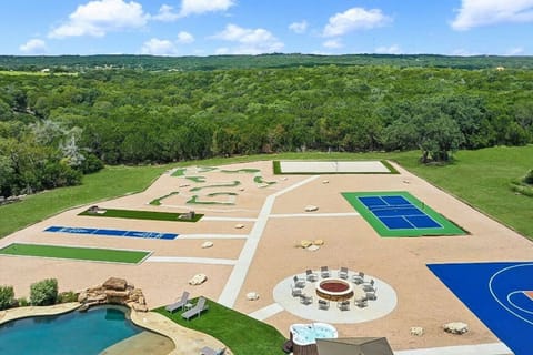 [Backyard] Aerial view of the outdoor amenities featuring a hot tub and fire pit, pickleball, volleyball, basketball and more