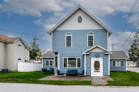 A blue and white house perched on a lush green field, like a fairytale cottage.