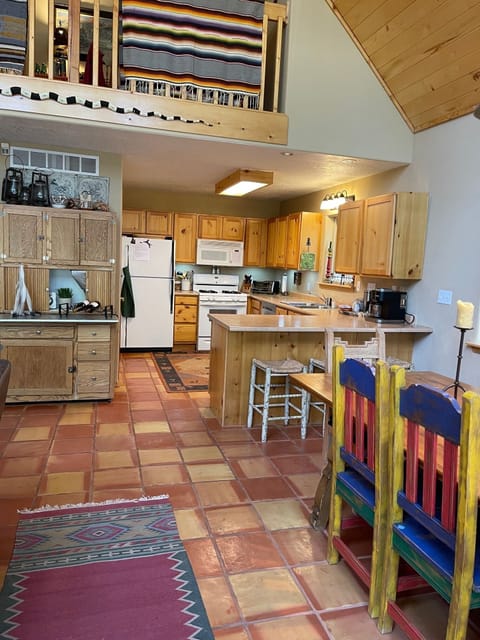 Dining table in foreground with fully-stocked kitchen and hutch. 