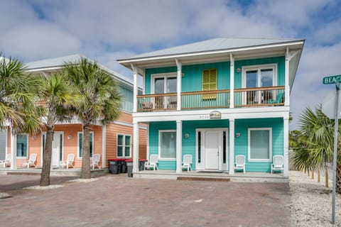 Charming turquoise beach house with tropical palms and front porch seating for the perfect coastal getaway.
