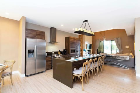 Chef-ready kitchen featuring sleek wood cabinetry, stainless appliances, and a long island seating 6 under a modern chandelier-open to the living room for easy gatherings.