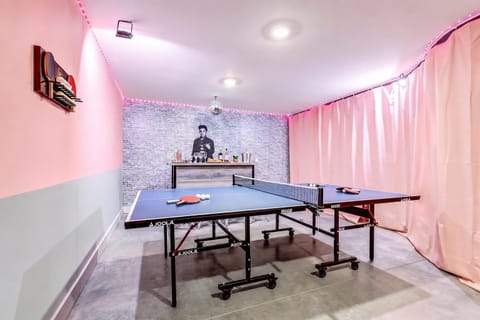 The converted garage karaoke lounge opens into a game room with ping pong, a full bar, and a disco ball spinning overhead. Late-night rounds happen here, and the pink and grey walls keep the energy high