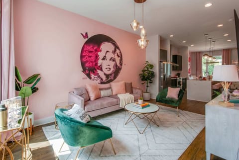 The Dolly-inspired home's living room wraps you in pink walls, a Dolly Parton mural, and neon that makes every gathering feel like a celebration