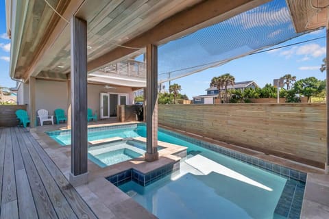 - Refreshing pool features a sun shelf and integrated spa with underwater seating
- Covered deck includes colorful Adirondack chairs for post swim relaxation
- Wood fencing and lush landscaping create a serene tropical vibe outdoors
