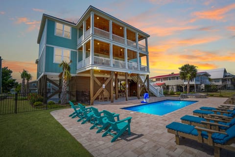 Coastal beach house featuring private pool, spacious multi-level balconies, and vibrant turquoise seating for memorable sunset evenings.