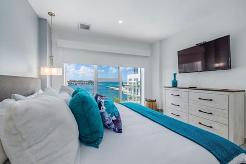 Sink into crisp white linens and vibrant turquoise accents as you wake to stunning waterfront views from your serene coastal retreat.