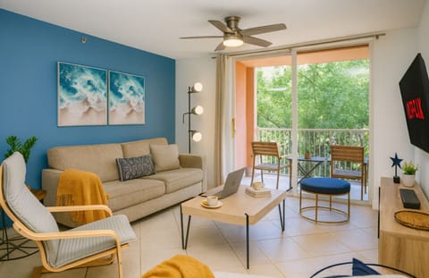 Bright living room with private balcony and peaceful tree views — perfect for relaxing after a beach day.