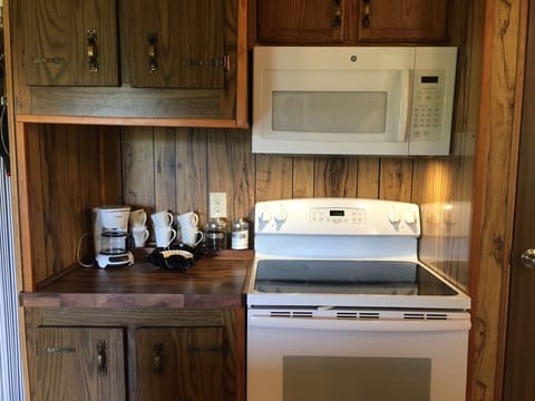 Kitchen with full size stove/oven & microwave. Drip coffee maker, filters, sugar