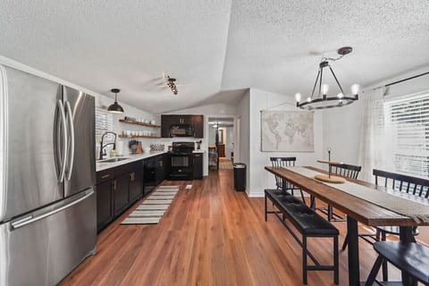Open kitchen and dining area with quartz countertops, stainless appliances, and nearby laundry room for added convenience.