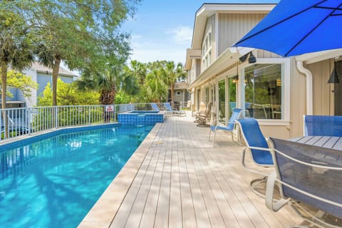 Turquoise waters shimmer beside a wide wooden deck, creating a serene spot for slow afternoons. Comfortable blue loungers and shaded dining areas invite you to breathe in the fresh air while surrounded by lush tropical greenery.
