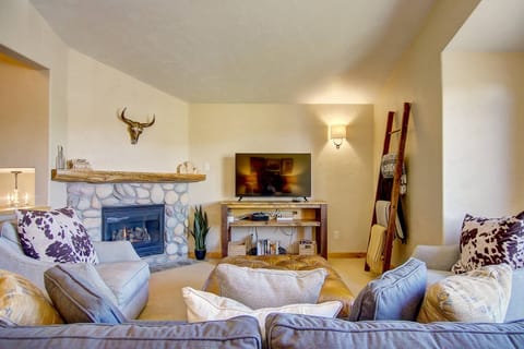 Relax fireside in this cozy mountain-inspired living room, complete with plush seating, a charming stone fireplace, and warm rustic touches throughout