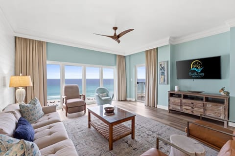 Relax in the cozy living room with plush seating, a large flat-screen TV, and panoramic windows that flood the space with natural light and showcase endless ocean views.
